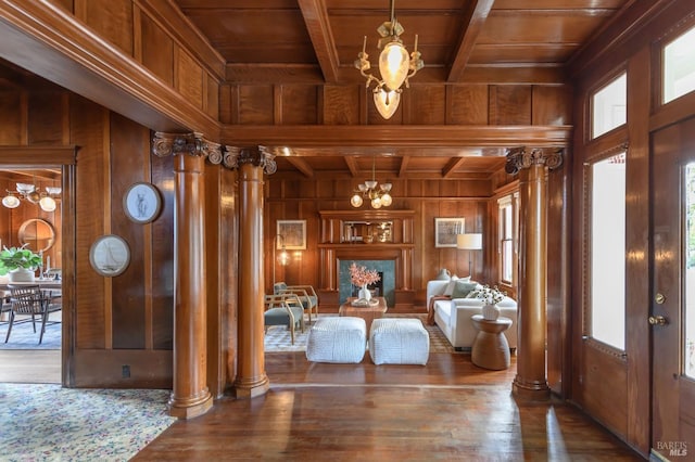 living room featuring wooden ceiling, wood walls, a chandelier, healthy amount of natural light, and decorative columns