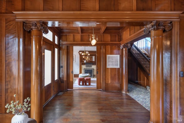 unfurnished dining area with wooden walls, dark wood-type flooring, wooden ceiling, beam ceiling, and a fireplace with raised hearth