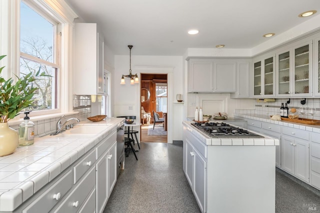 kitchen featuring stainless steel appliances, a sink, tile countertops, backsplash, and recessed lighting