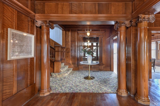 entrance foyer with wood walls, wood-type flooring, and decorative columns
