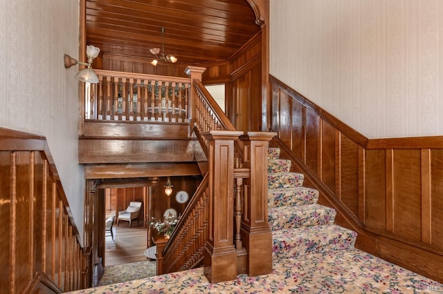 stairway featuring wood ceiling, wallpapered walls, and wood finished floors