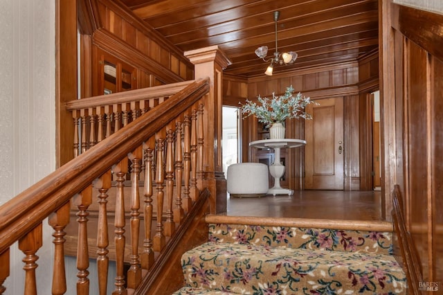 staircase featuring wood ceiling, a chandelier, and wooden walls
