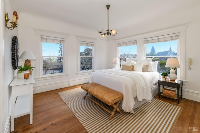 bedroom featuring hardwood / wood-style flooring, a chandelier, and baseboards