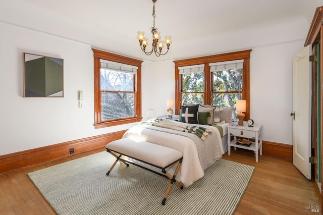 bedroom featuring baseboards, a chandelier, and wood finished floors
