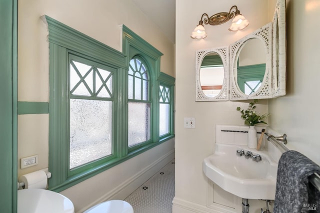 bathroom featuring a sink, baseboards, tile patterned floors, and toilet