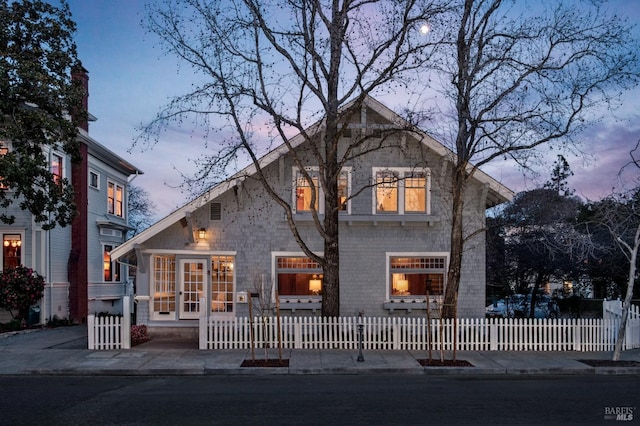 back of house at dusk featuring a fenced front yard