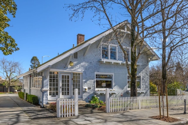 back of property featuring a chimney and a fenced front yard