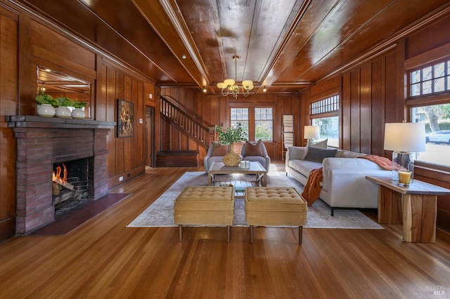 living area with a brick fireplace, wood finished floors, wood walls, stairway, and wood ceiling