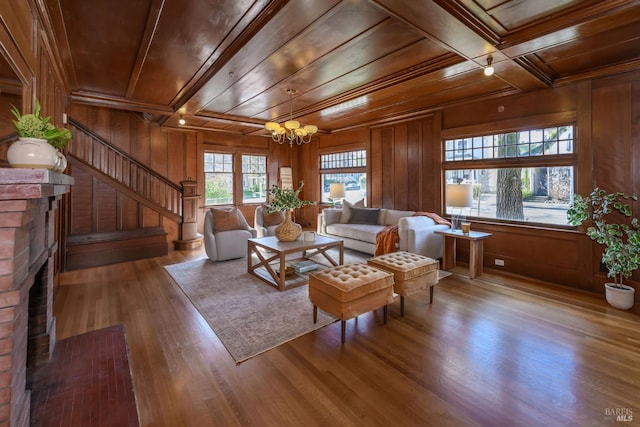 living area featuring wooden ceiling, a chandelier, stairs, wood finished floors, and a brick fireplace