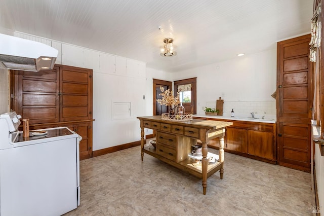 kitchen with electric range, light countertops, a sink, brown cabinetry, and light flooring