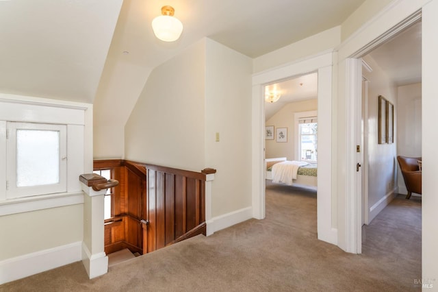 hallway featuring an upstairs landing, carpet, vaulted ceiling, and baseboards