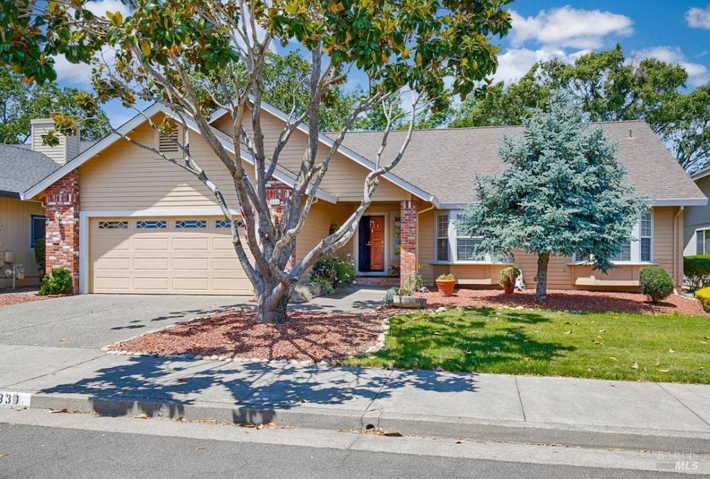 view of front of property featuring a garage, a front lawn, roof with shingles, and driveway