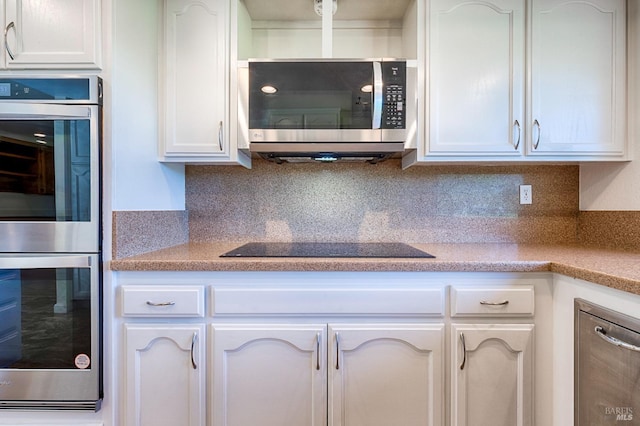 kitchen featuring light countertops, white cabinets, stainless steel appliances, and backsplash