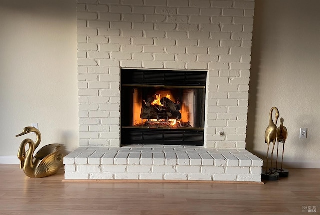 details with a brick fireplace, baseboards, and wood finished floors