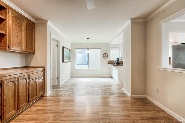 interior space featuring a textured ceiling, ornamental molding, and light wood-style flooring