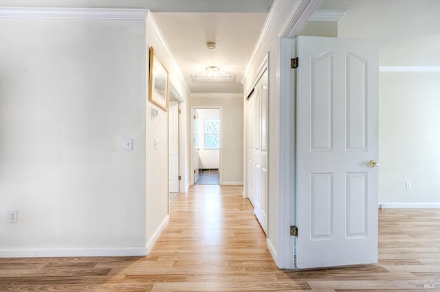 hall with light wood finished floors, baseboards, and ornamental molding