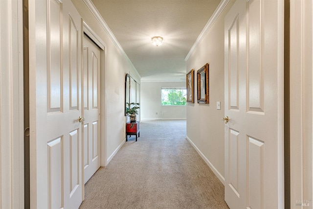 hallway featuring baseboards, crown molding, and light colored carpet
