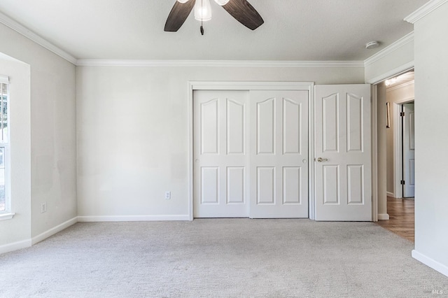 unfurnished bedroom with a closet, baseboards, ornamental molding, ceiling fan, and carpet floors