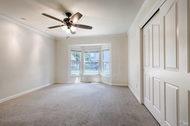 unfurnished bedroom with baseboards, ceiling fan, crown molding, and carpet floors