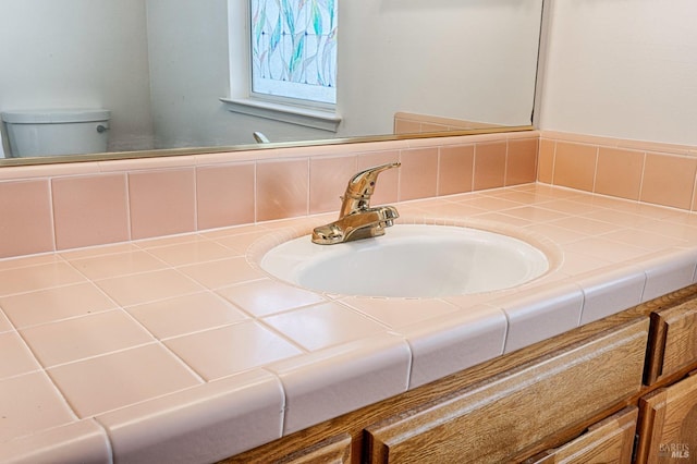 half bath with tasteful backsplash, toilet, and vanity
