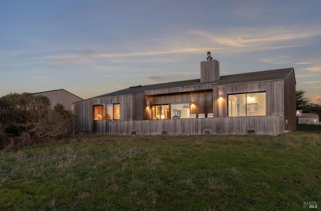 back house at dusk featuring a yard