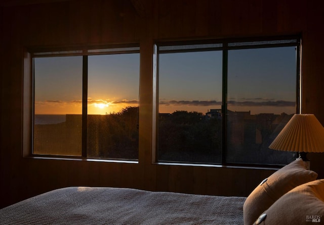 bedroom featuring multiple windows and wooden walls