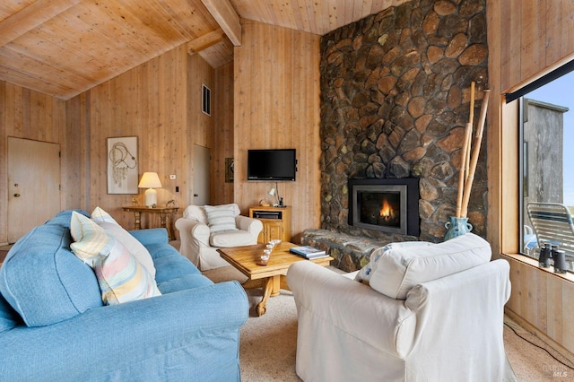 carpeted living room featuring wood ceiling, a stone fireplace, beamed ceiling, and wood walls