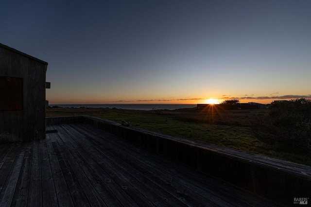 deck at dusk featuring a water view