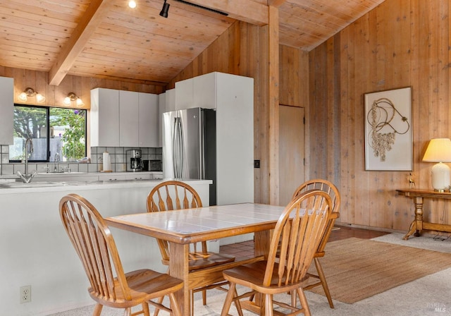 dining room with vaulted ceiling with beams, wood ceiling, and wooden walls