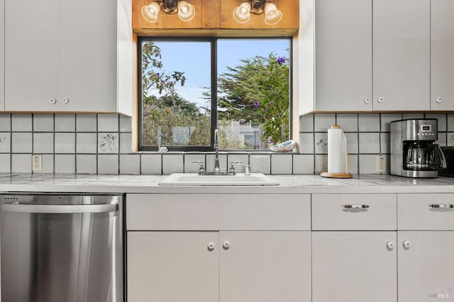 kitchen with white cabinetry, sink, decorative backsplash, and stainless steel dishwasher