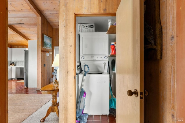 laundry room featuring stacked washer / dryer, wooden walls, and wooden ceiling