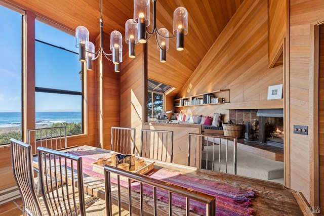 dining area featuring wood ceiling, a tile fireplace, a water view, a notable chandelier, and tile patterned floors