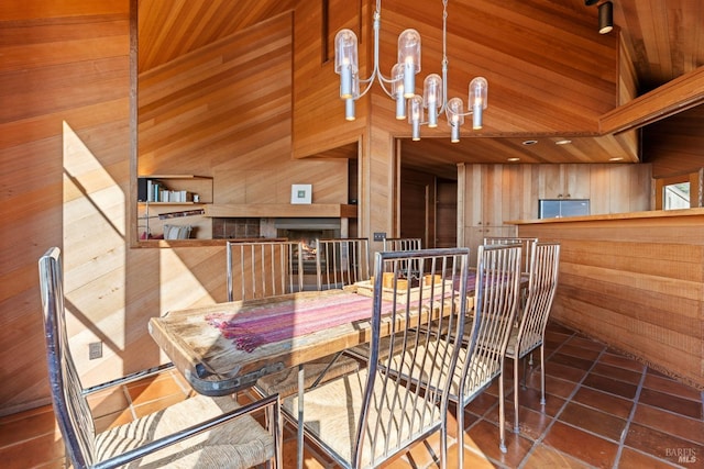 dining room featuring tile patterned flooring, a chandelier, wood ceiling, and wooden walls