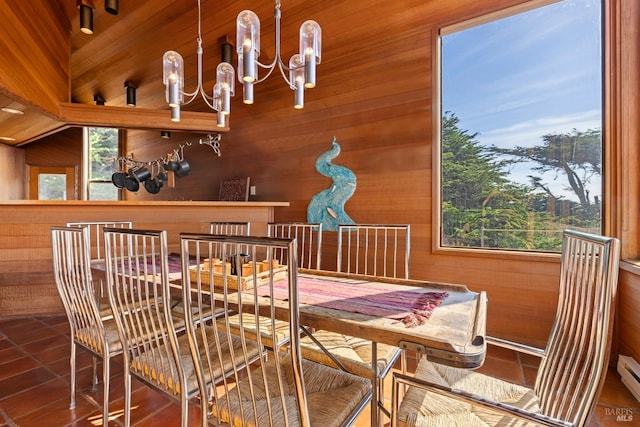 dining space with a baseboard radiator, a chandelier, tile patterned flooring, and wood walls