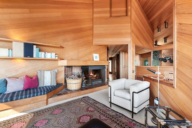 living room featuring a towering ceiling, wooden walls, and a tiled fireplace