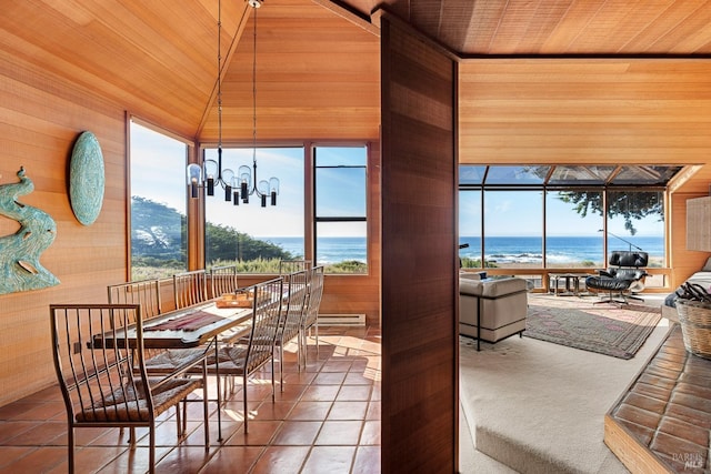 dining room with tile patterned flooring, vaulted ceiling, a water view, and a chandelier