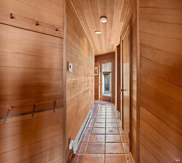 corridor featuring tile patterned flooring, a baseboard radiator, wooden ceiling, and wooden walls