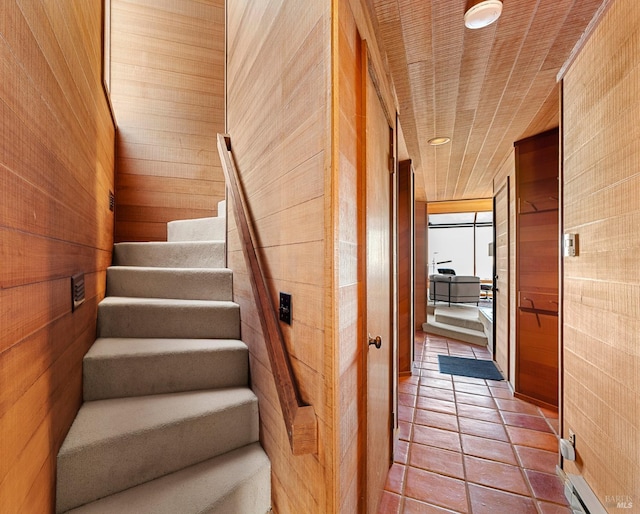 stairs featuring wooden walls, tile patterned flooring, and wooden ceiling