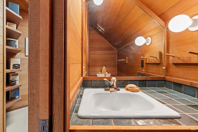 bathroom featuring lofted ceiling, sink, wood ceiling, and wooden walls