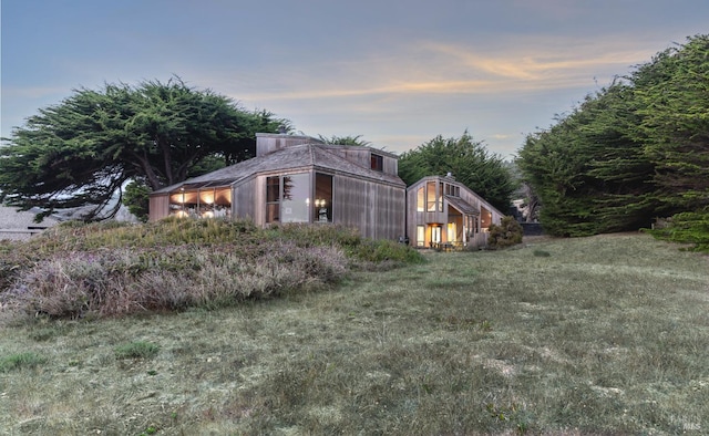 property exterior at dusk featuring a yard