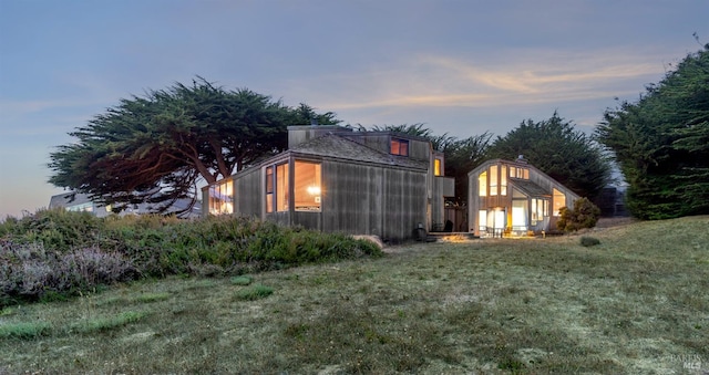 back house at dusk featuring a yard