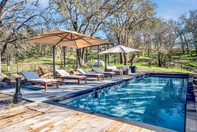 pool featuring fence, outdoor lounge area, and a wooden deck