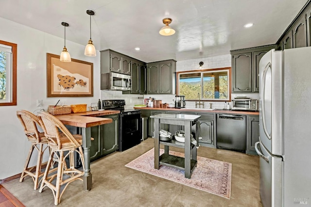 kitchen with wooden counters, tasteful backsplash, a sink, and stainless steel appliances