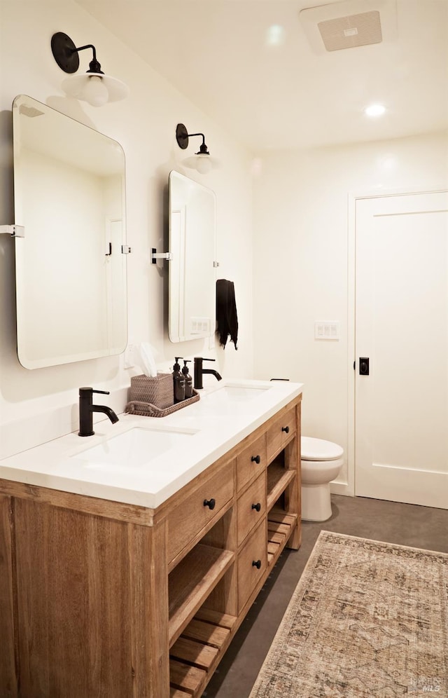 bathroom featuring double vanity, a sink, and toilet