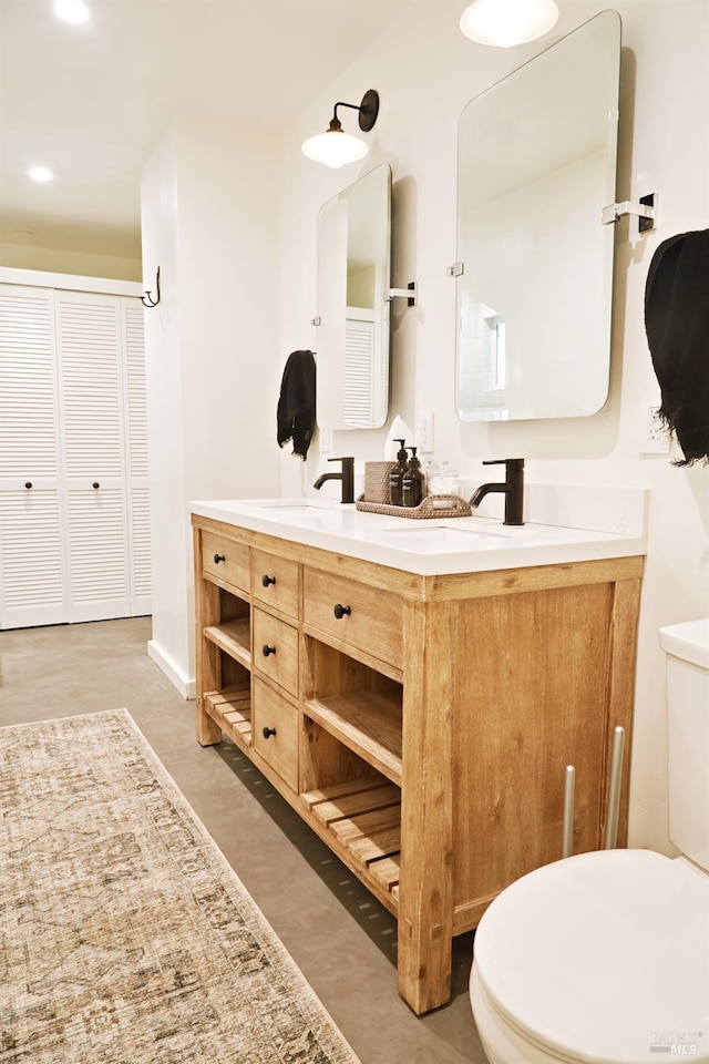 bathroom with double vanity, a closet, a sink, and toilet