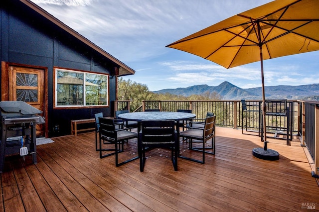 wooden deck with outdoor dining space and a mountain view