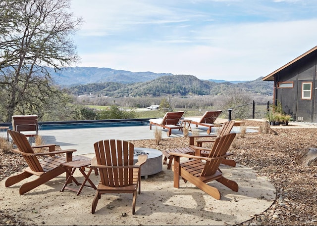 view of patio with a pool, a mountain view, and a fire pit