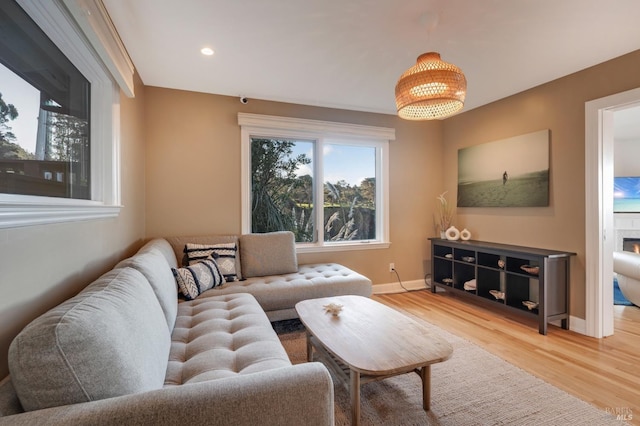 living area with a fireplace, recessed lighting, wood finished floors, and baseboards