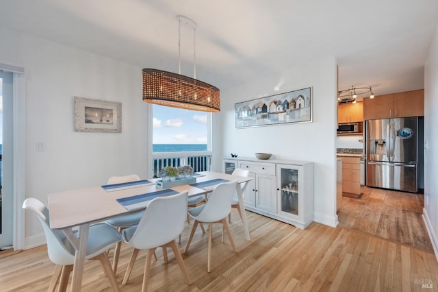 dining space featuring light wood-style floors and a water view