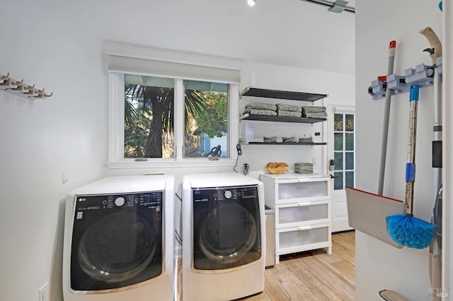 clothes washing area featuring light wood-type flooring, laundry area, and washer and dryer